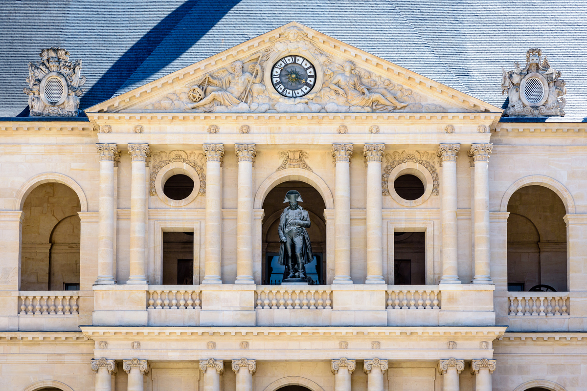 Front view of the southern facade of the court of honor of the Hotel des Invalides in Paris, France, with the statue of Napoleon Bonaparte by french sculptor Charles Emile Seurre on the balcony.